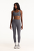 Woman wearing a gray sports bra and leggings set on a white background