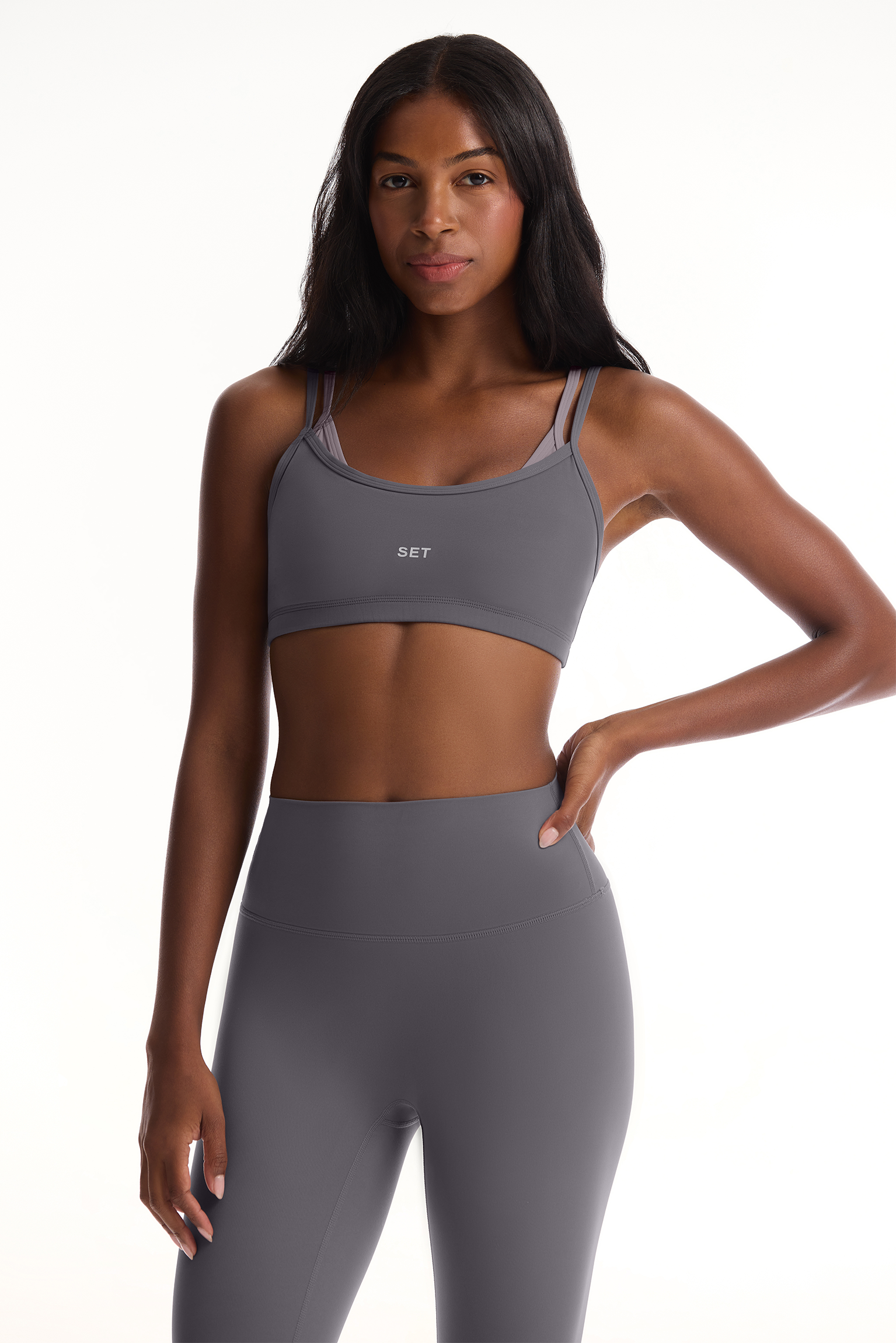 Woman wearing a gray sports bra and leggings set on a white background <model-info>Autumn wears a size S and is 5’7½”, 25” waist, 32” bust.</model-info>