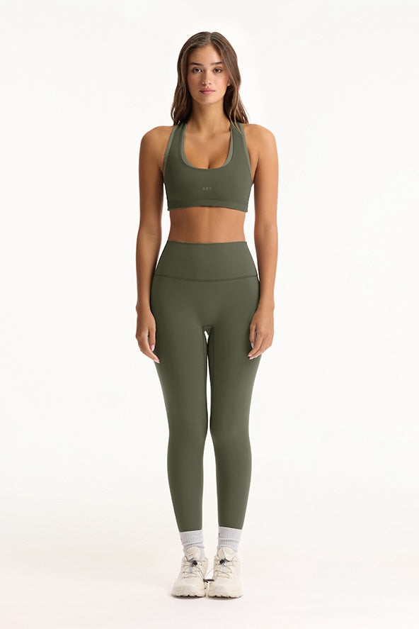 Woman wearing a green sports bra and leggings set on a white background