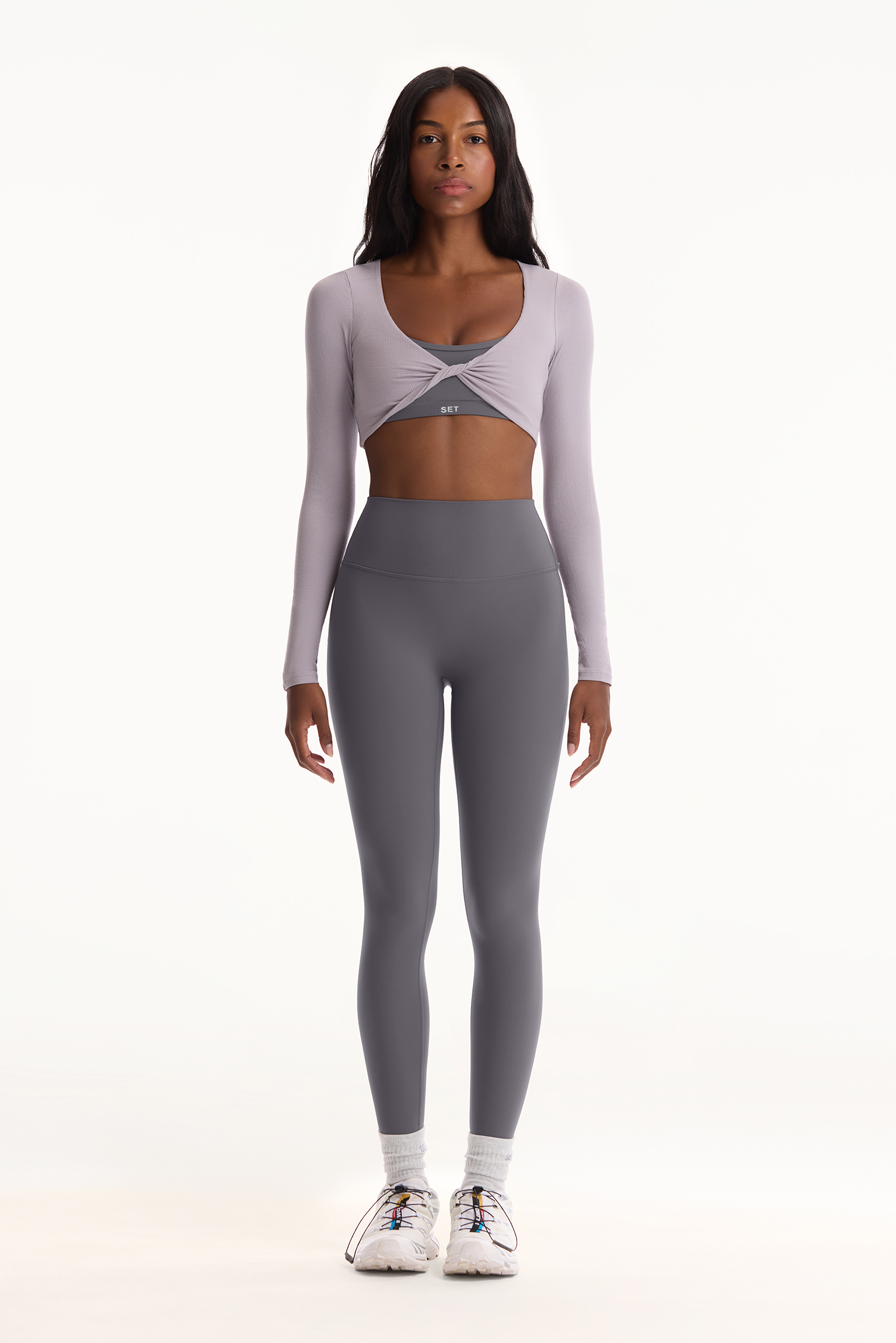 Woman wearing a gray athletic outfit on a white background