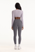 Person wearing a light gray long-sleeve top and dark gray leggings on a white background
