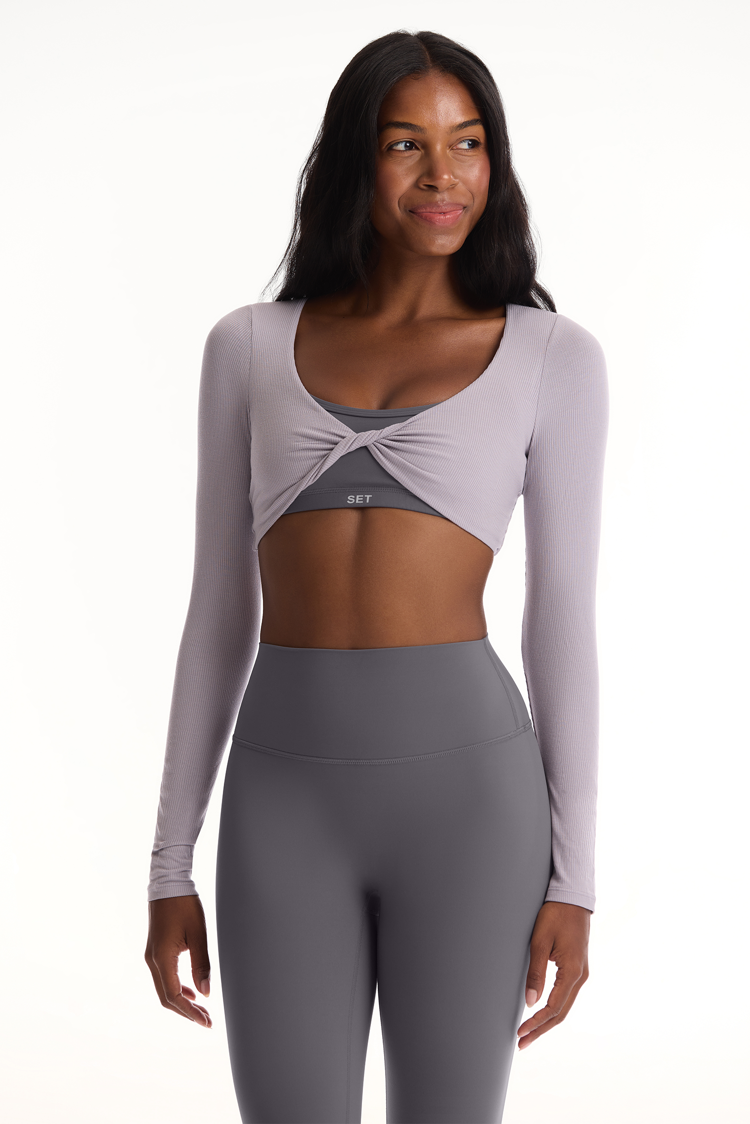 Woman wearing a gray athletic outfit with long sleeves and leggings on a white background <model-info>Autumn wears a size S and is 5’7½”, 25” waist, 32” bust.</model-info>