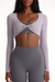 Woman wearing a gray long-sleeve athletic top and leggings with 'SET' branding.