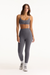 Woman wearing a gray sports bra and leggings set on a white background