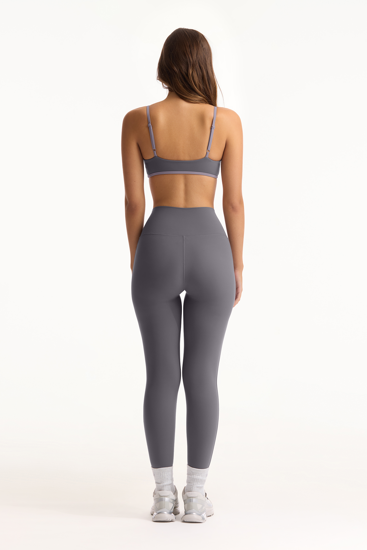 Person wearing a gray sports bra and leggings set on a white background