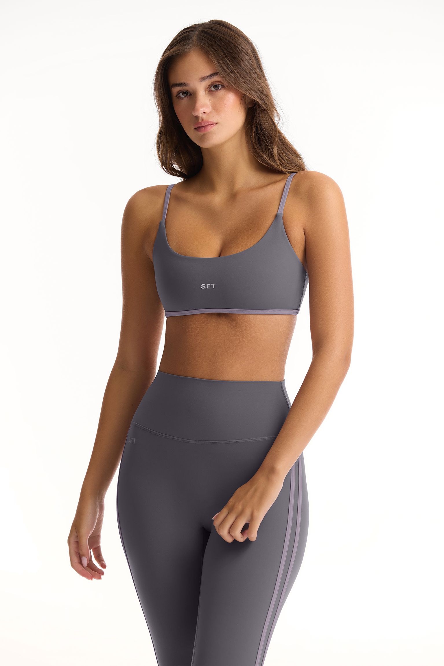 Woman wearing a gray sports bra and leggings set on a white background <model-info>Sophie wears a size S and is 5’9½”, 23” waist, 34CD bust.</model-info>