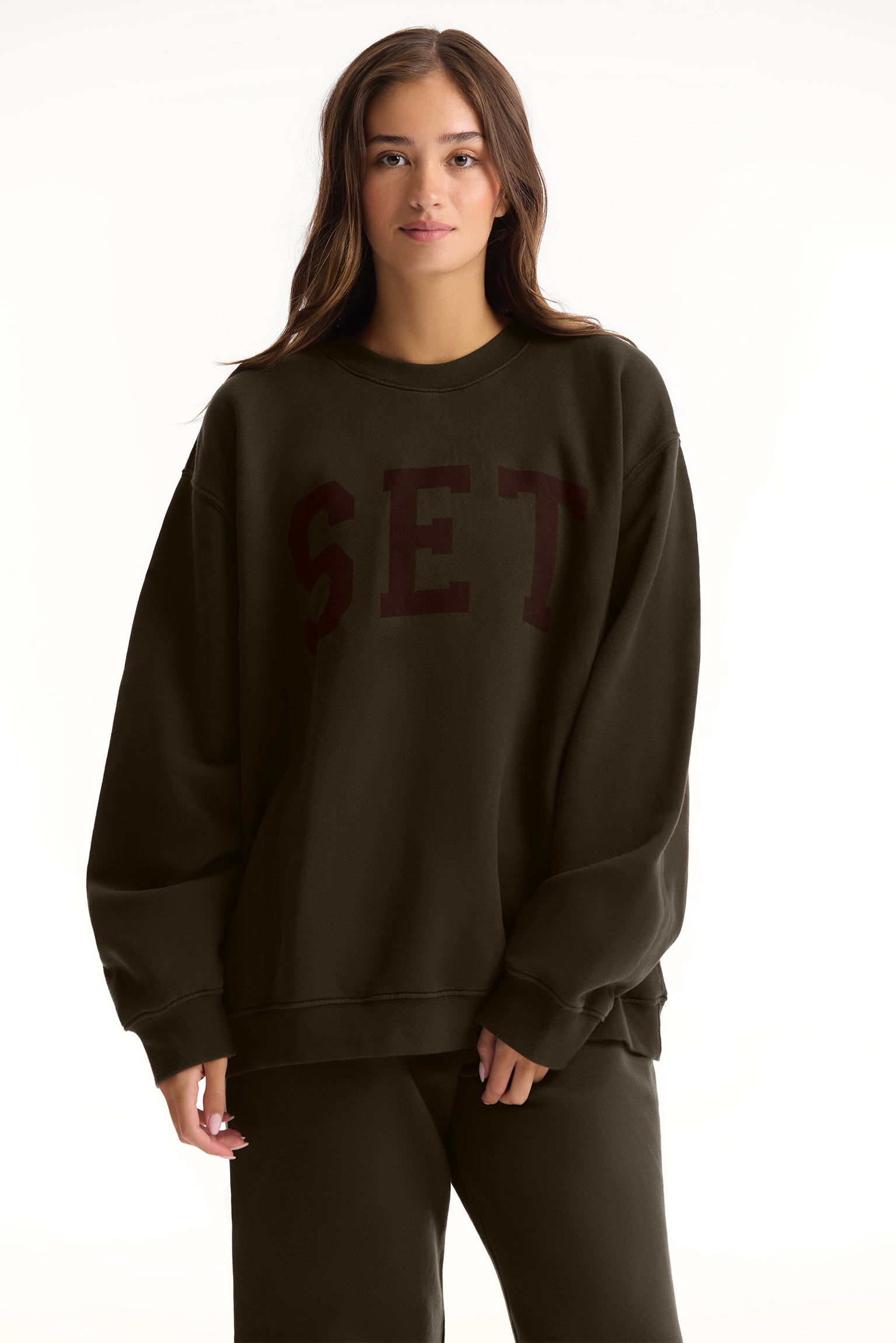 Person wearing a dark brown sweatshirt with 'SET' text on a white background <model-info>Sophie wears a size L and is 5’9½”, 23” waist, 34CD bust.</model-info>