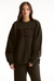 Person wearing a dark brown sweatshirt with 'SET' text on a white background <model-info>Sophie wears a size L and is 5’9½”, 23” waist, 34CD bust.</model-info>