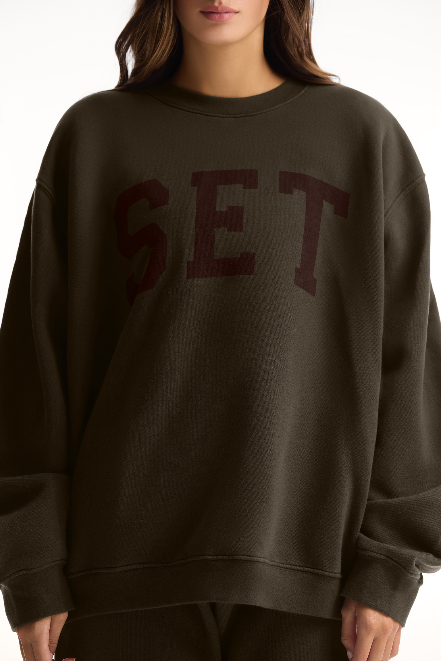 Person wearing a dark green sweatshirt with 'SET' printed on it against a white background