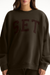 Person wearing a dark green sweatshirt with 'SET' printed on it against a white background