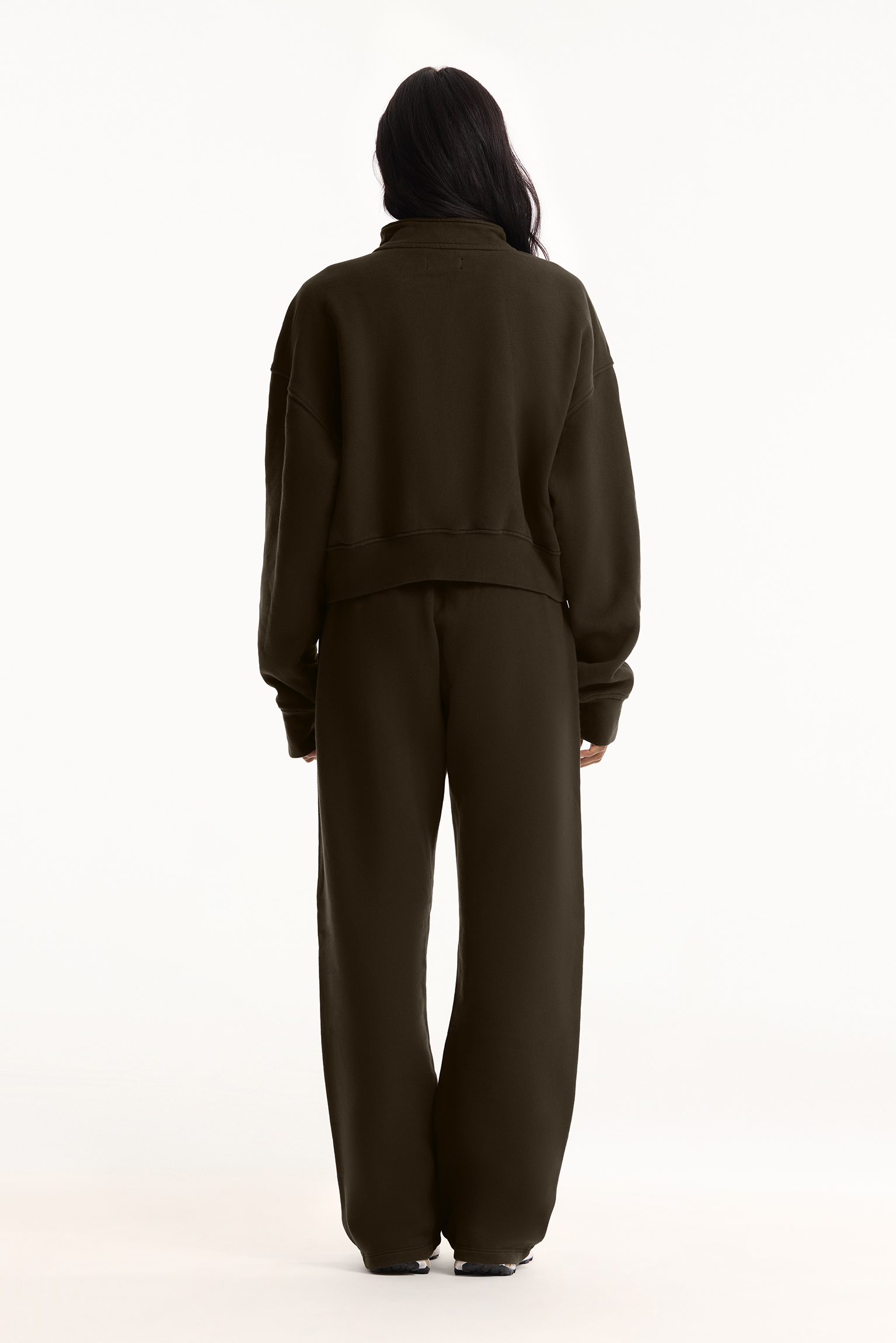 Person wearing a dark green tracksuit on a white background