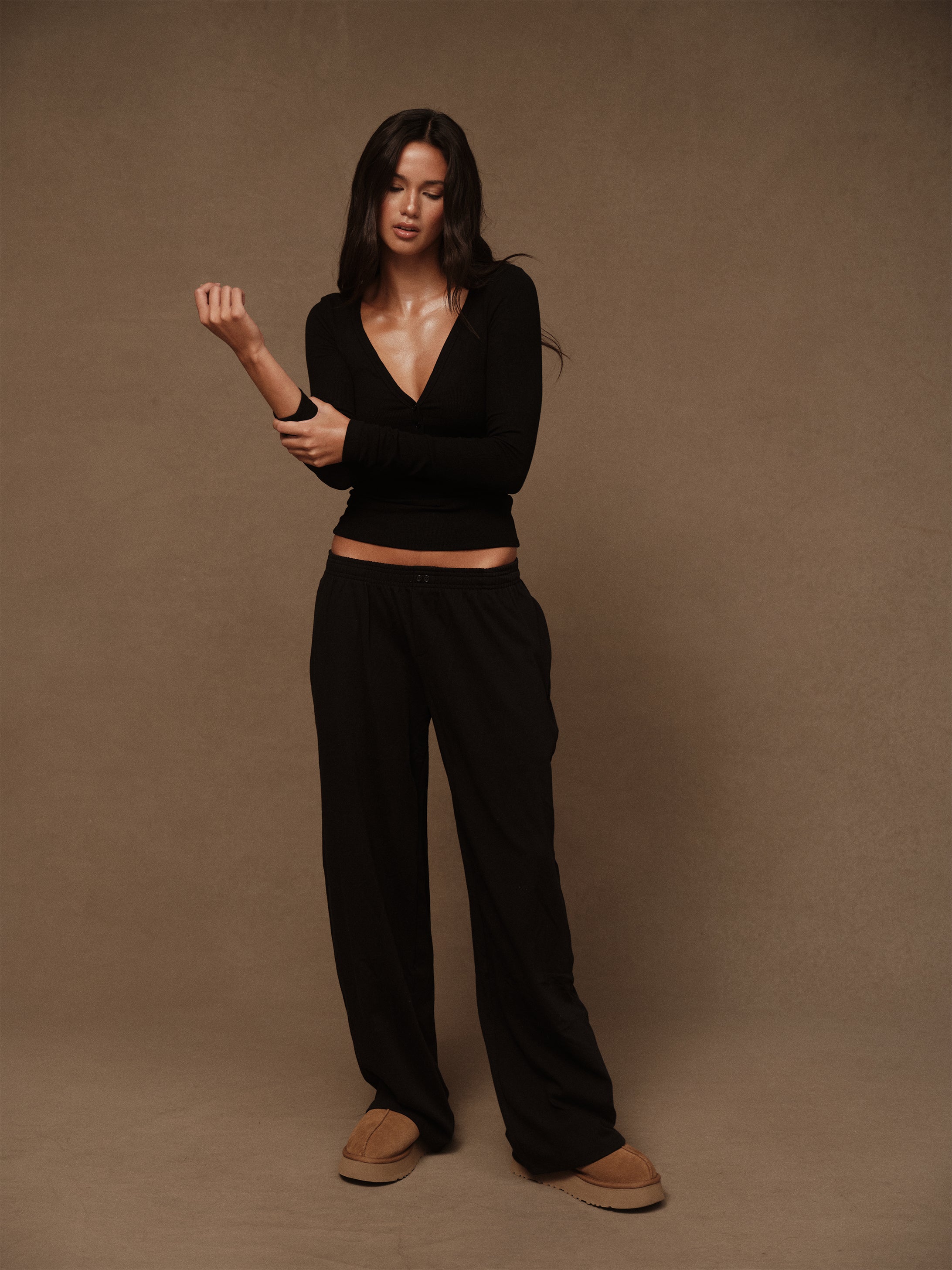 Woman wearing a black outfit against a brown background