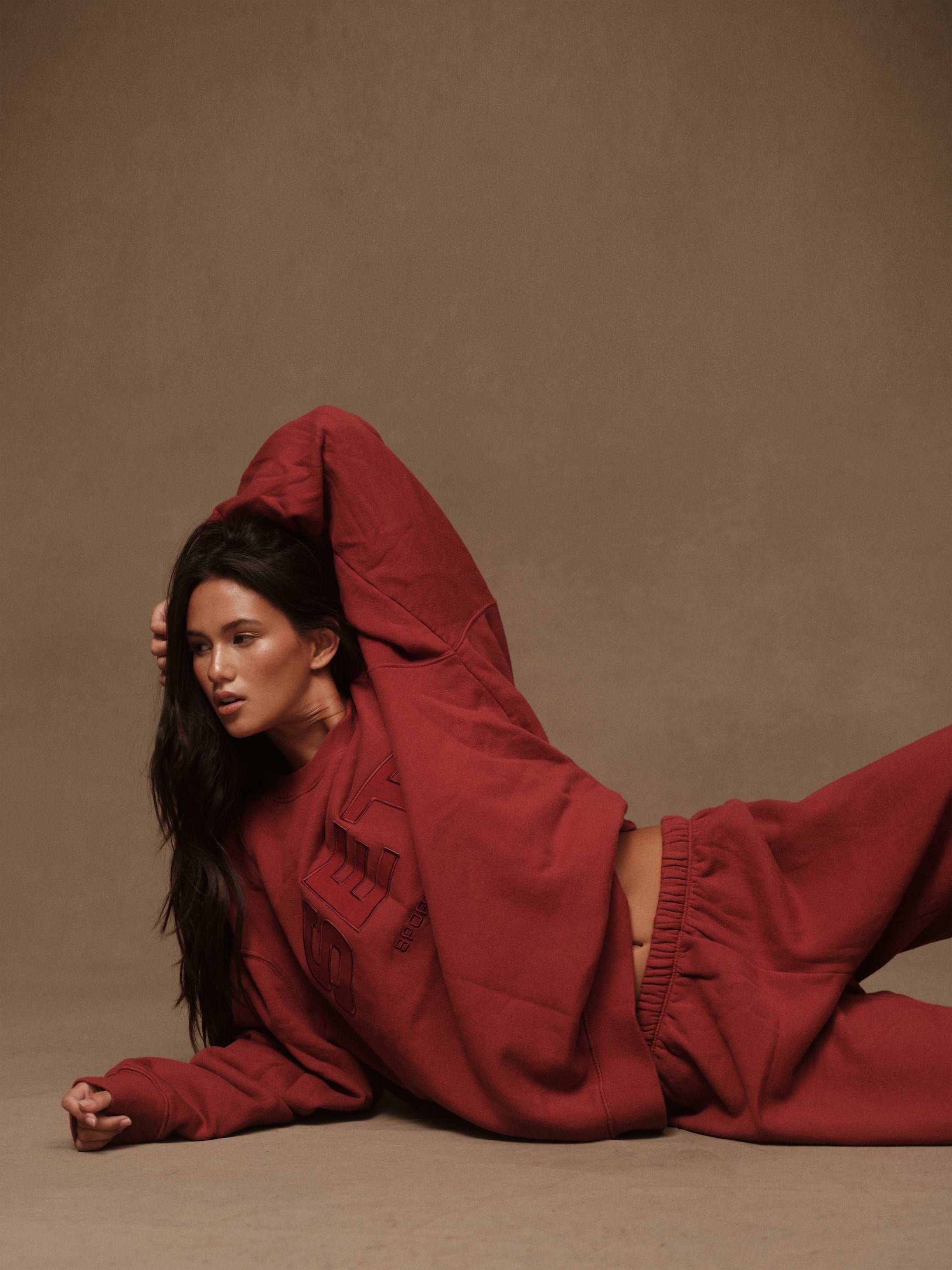 Person wearing a red outfit against a brown background