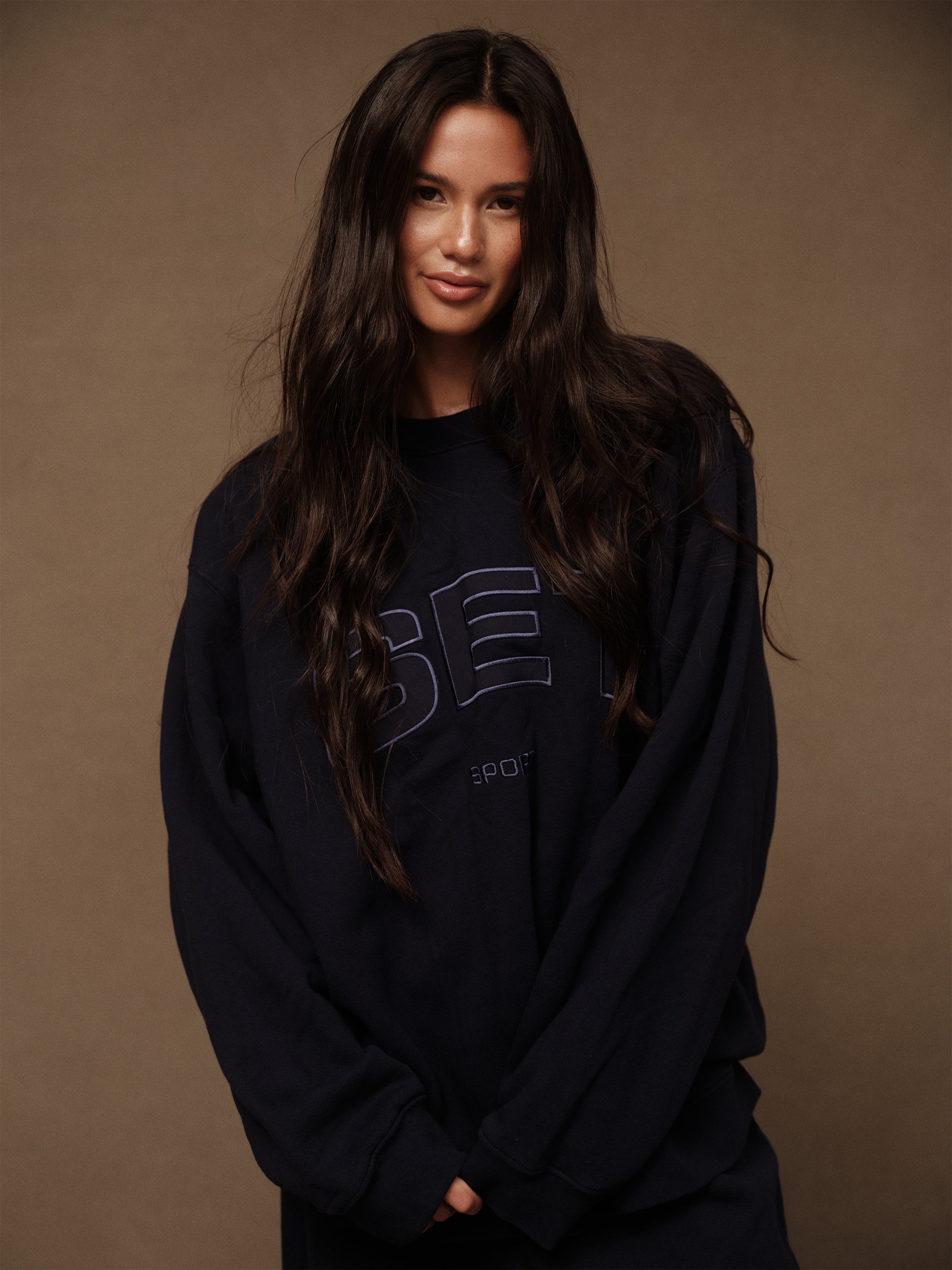 Woman wearing a dark blue sweatshirt with text on a brown background