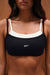 Black sports bra with white accents and 'SET' logo on a neutral background