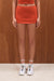 Person wearing a red skirt, white sneakers with colorful laces, and striped socks against a wooden background. <model-info>Grace wears a size XS and is 5'8", 25" waist, 32" bust.</model-info>