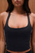 Person wearing a black tank top against a wooden background