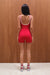 Person wearing a red unitard standing against a wooden wall.