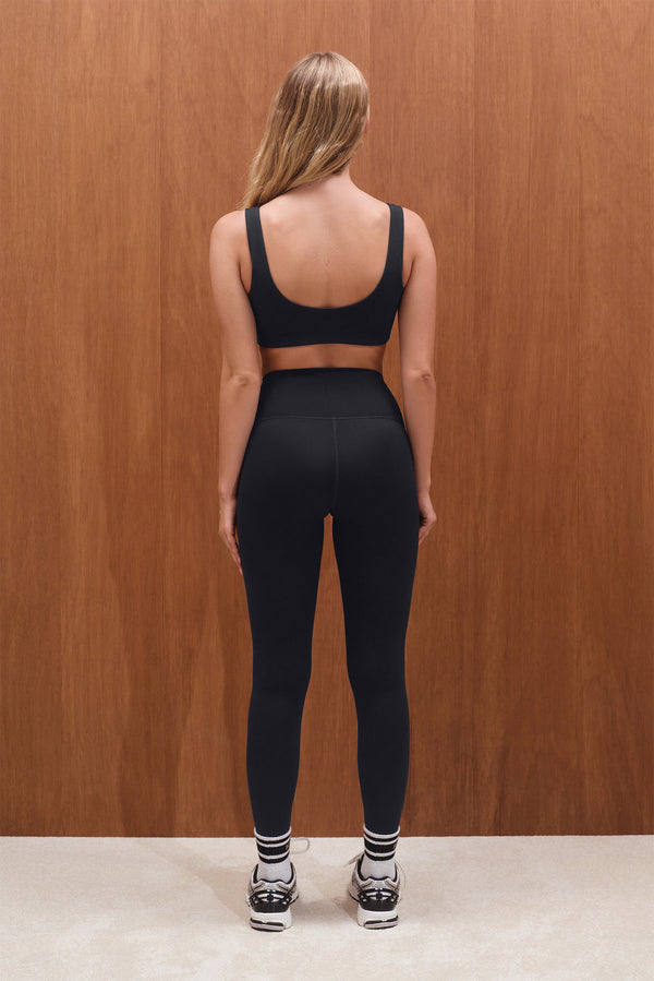 Person wearing a black sports bra and leggings set with a wooden background