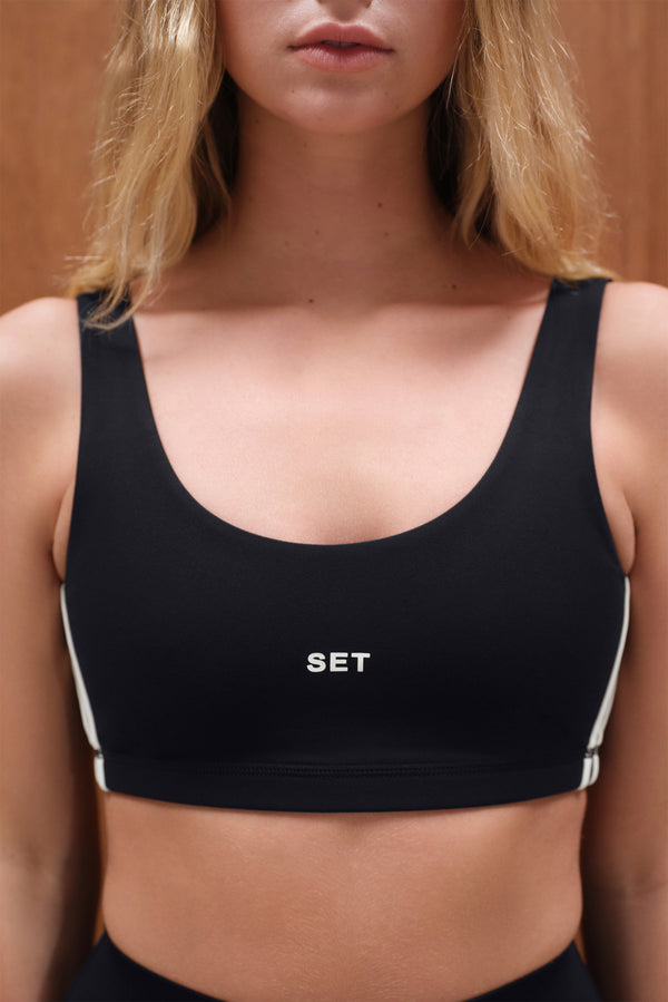 Black sports bra with 'SET' logo worn by a person against a neutral background