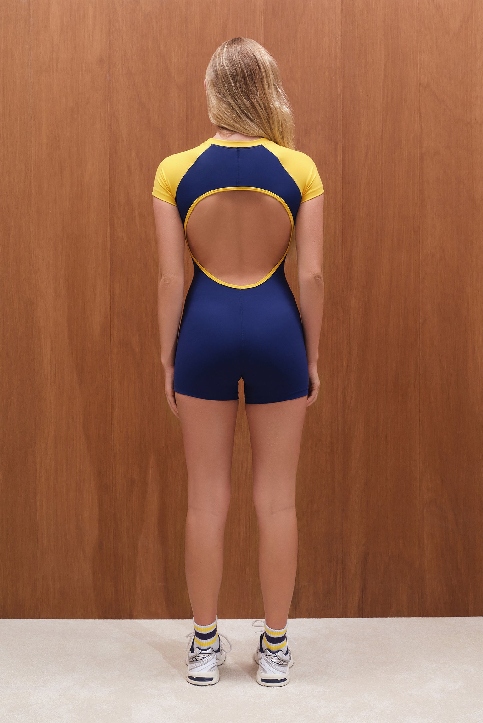 Person wearing a blue and yellow outfit with cut-out design on a wooden background