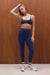 Woman wearing a blue athletic outfit with yellow accents against a wooden background