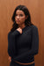 Woman wearing a black long-sleeve top against a wooden background <model-info>Sydnee wears a size XS and is 5'8", 22” waist, 32BB bust.</model-info>