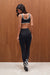 Woman wearing a black sports bra and leggings standing against a wooden wall.