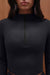 Black long-sleeve top with a quarter zip on a brown background