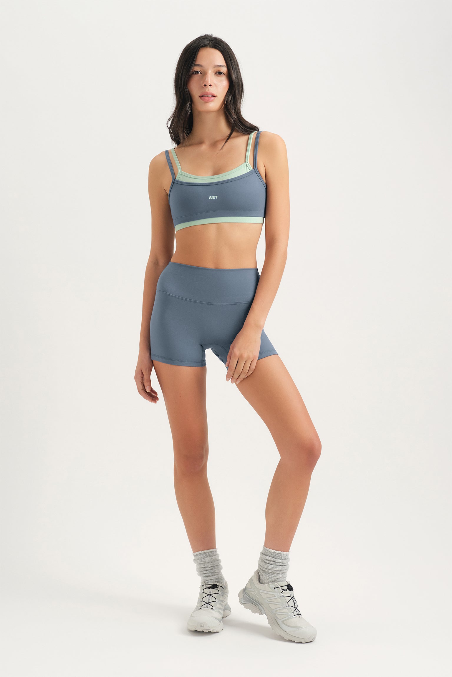 Woman wearing a sports bra and shorts set on a white background