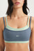 Woman wearing a blue and green sports bra with 'SET' branding on a white background
