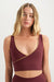 Woman wearing a burgundy sports bra with gold trim on a white background <model-info>Grace wears a size XS and is 5'8", 25" waist, 32" bust.</model-info>
