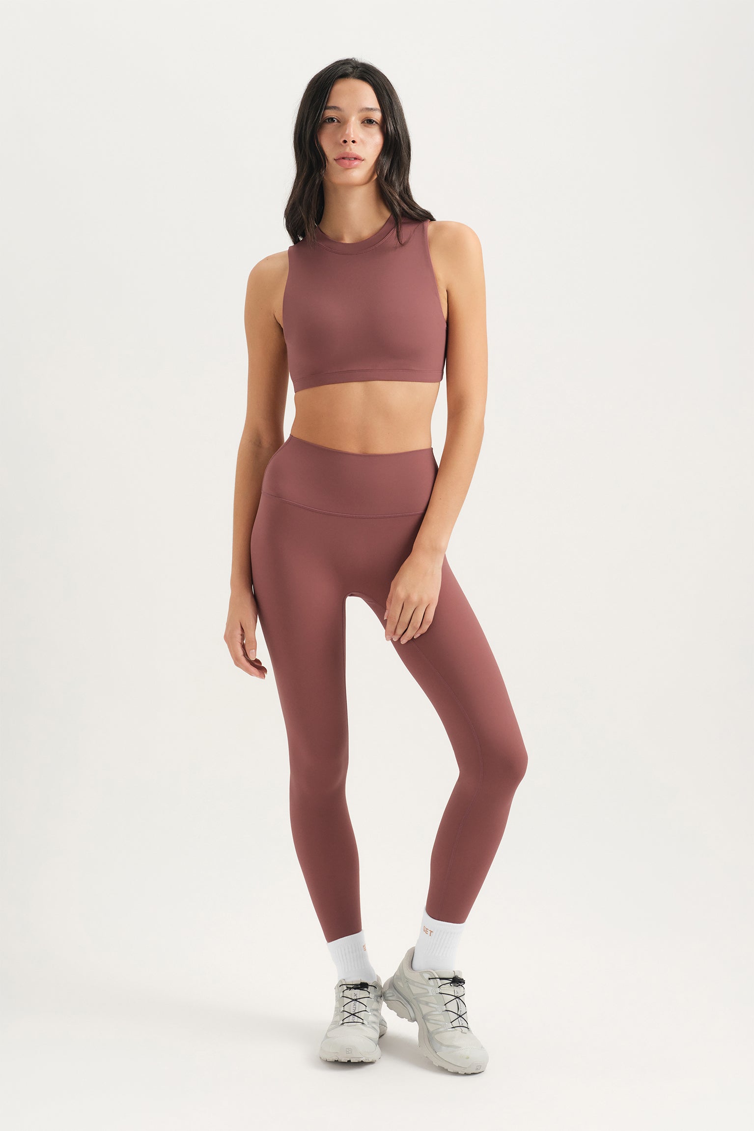 Woman wearing a mauve athletic outfit on a white background