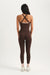 Person wearing a brown jumpsuit with criss-cross straps on a white background