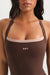 Brown tank top with 'SET' logo worn by a person on a white background