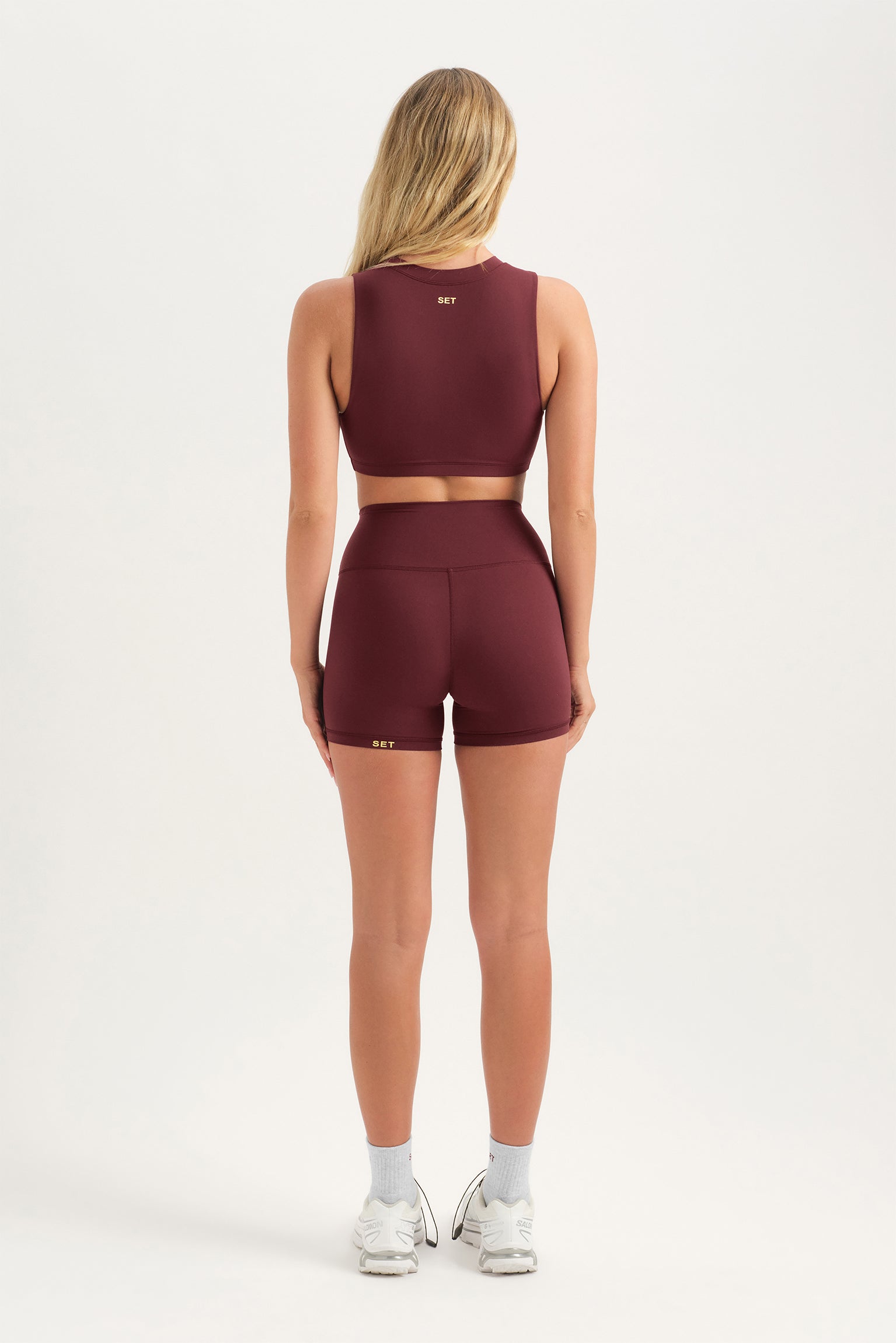 Person wearing a burgundy athletic outfit on a white background