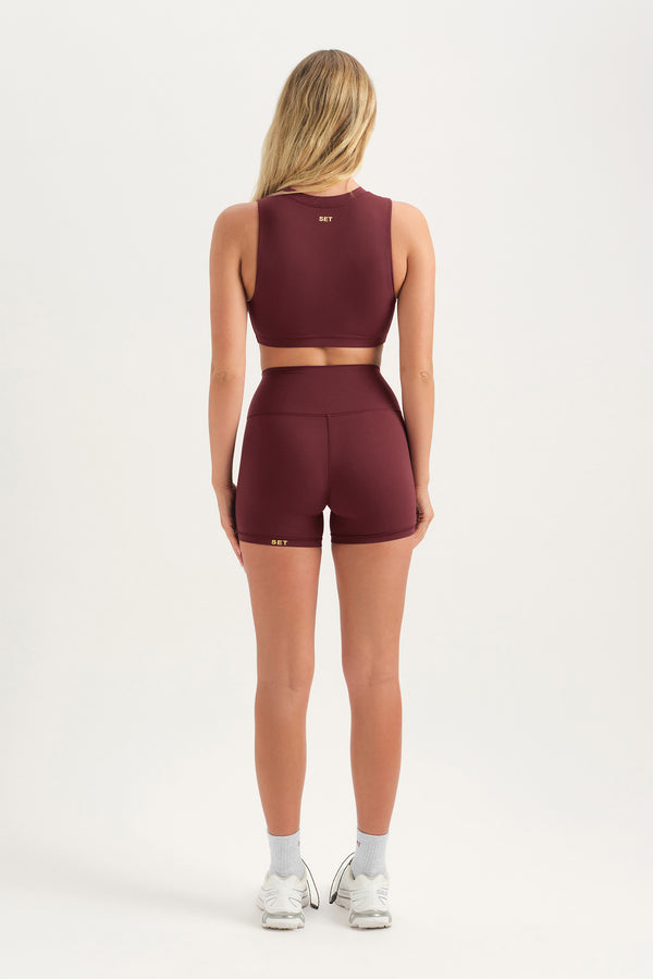 Person wearing a burgundy athletic outfit on a white background