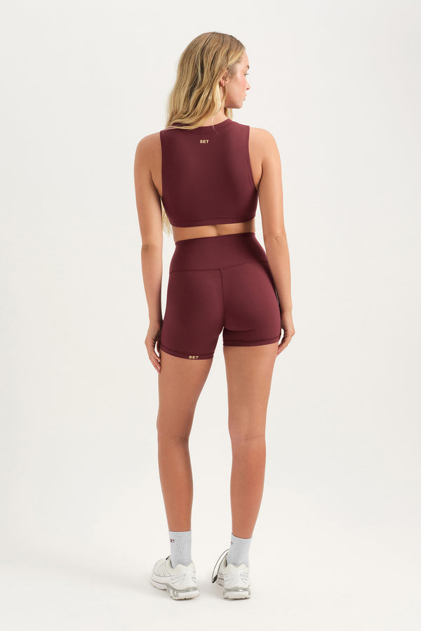 Woman wearing a maroon athletic outfit on a white background