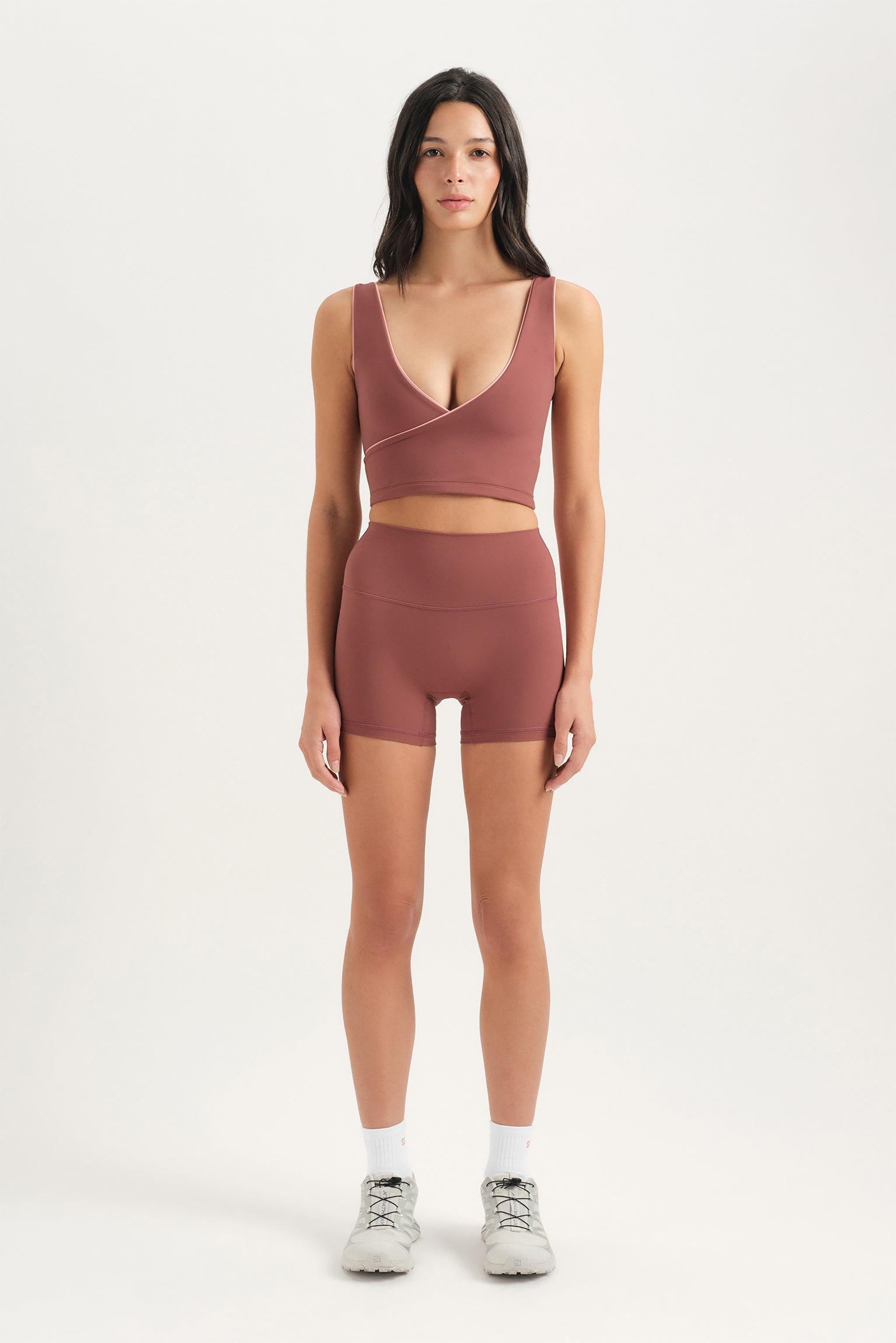 Woman wearing a brown sports bra and shorts set on a white background