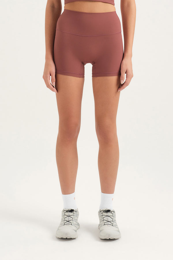Person wearing brown athletic shorts on a white background 
