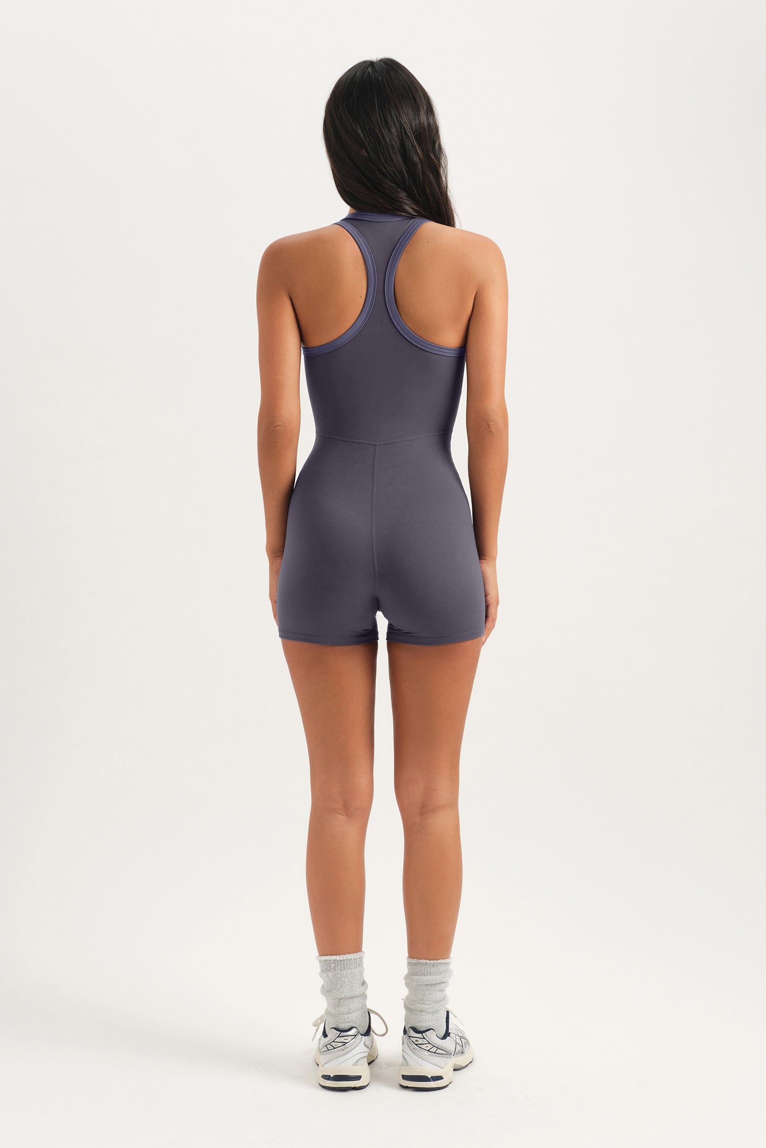 Person wearing a gray bodysuit on a white background