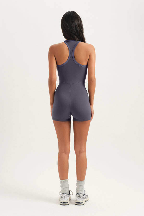 Person wearing a gray bodysuit on a white background