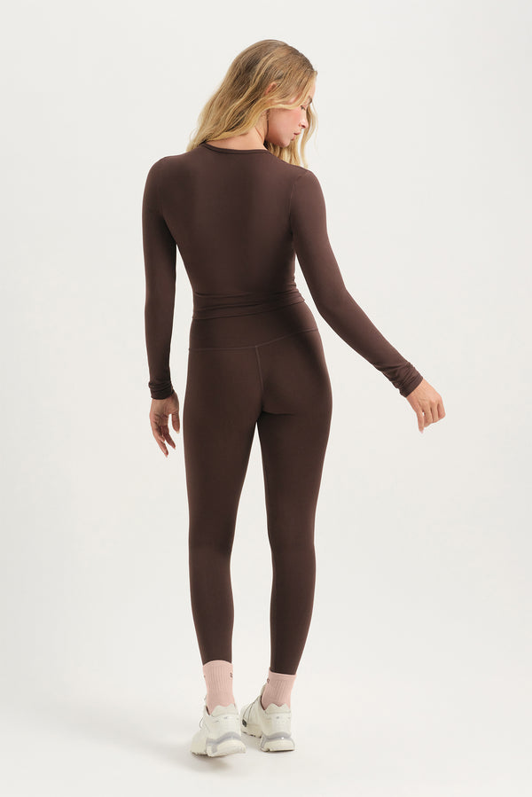 Person wearing a brown bodysuit on a white background