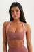 Woman wearing a pink sports bra with 'SET' branding on a white background <model-info>Sydnee wears a size XS and is 5'8", 22” waist, 32BB bust.</model-info>