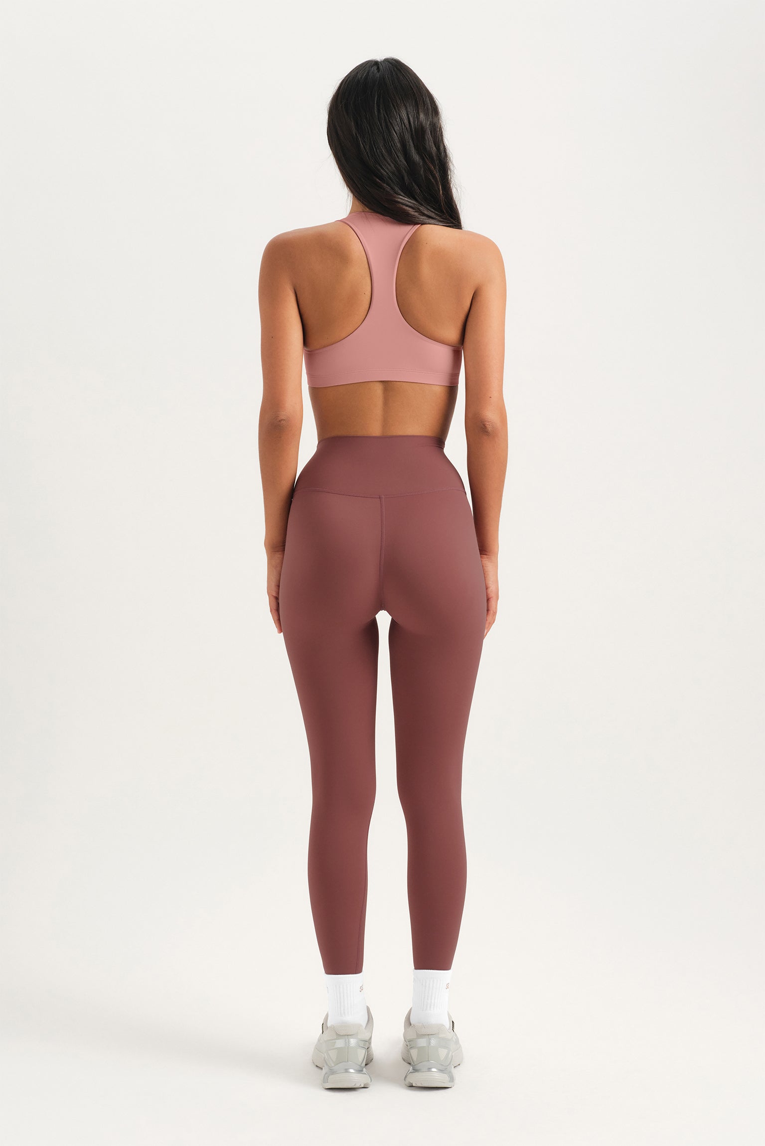 Person wearing a pink sports bra and leggings on a white background