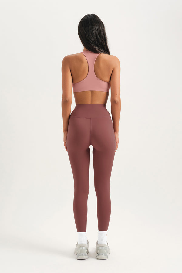 Person wearing a pink sports bra and leggings on a white background