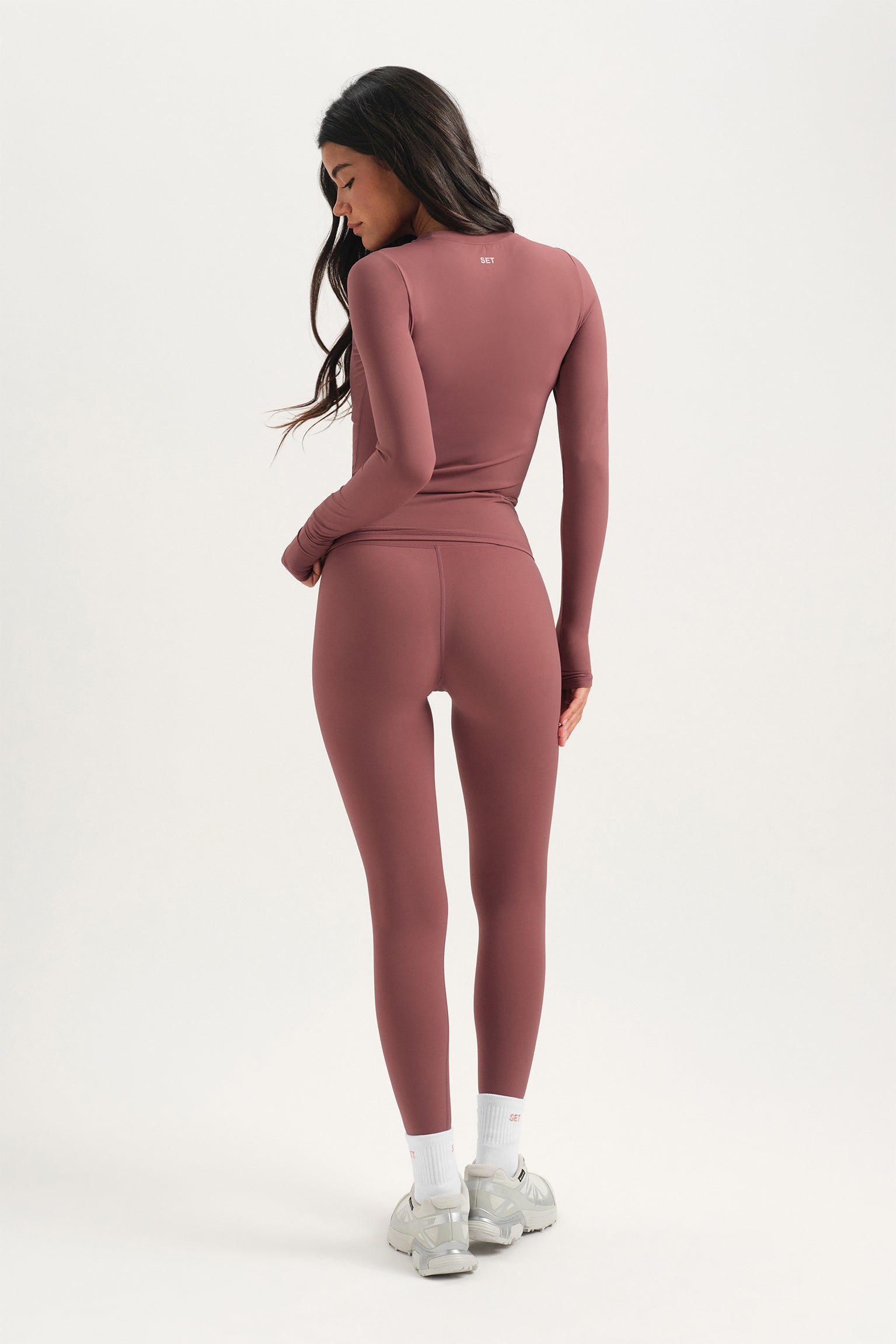 Woman wearing a pink long-sleeve top and leggings set on a white background