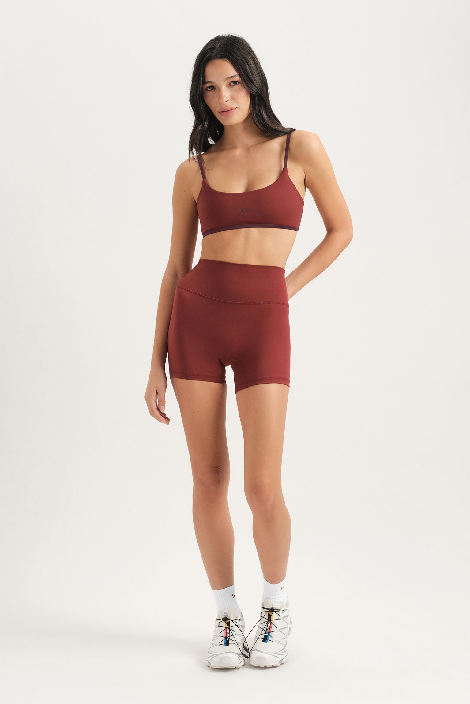 Woman wearing a red sports bra and shorts set on a white background