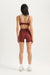 Person wearing a burgundy sports bra and shorts set on a white background