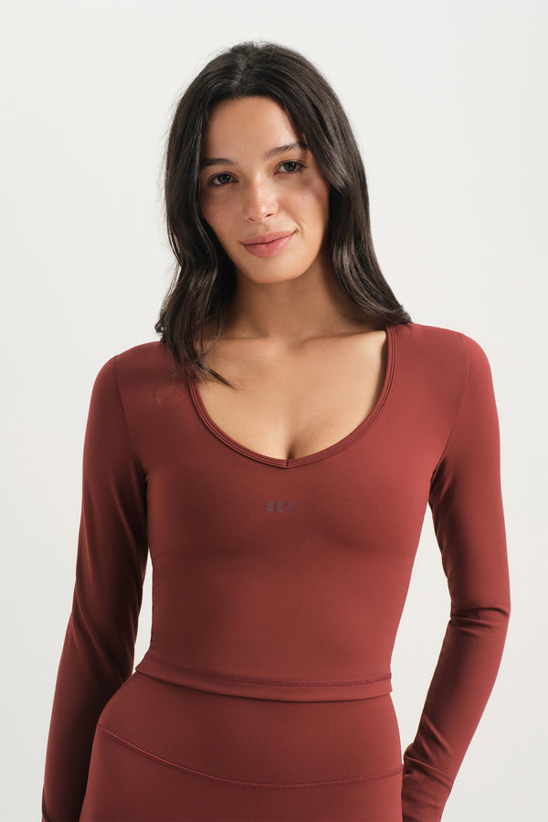 Woman wearing a red long-sleeve top on a white background 